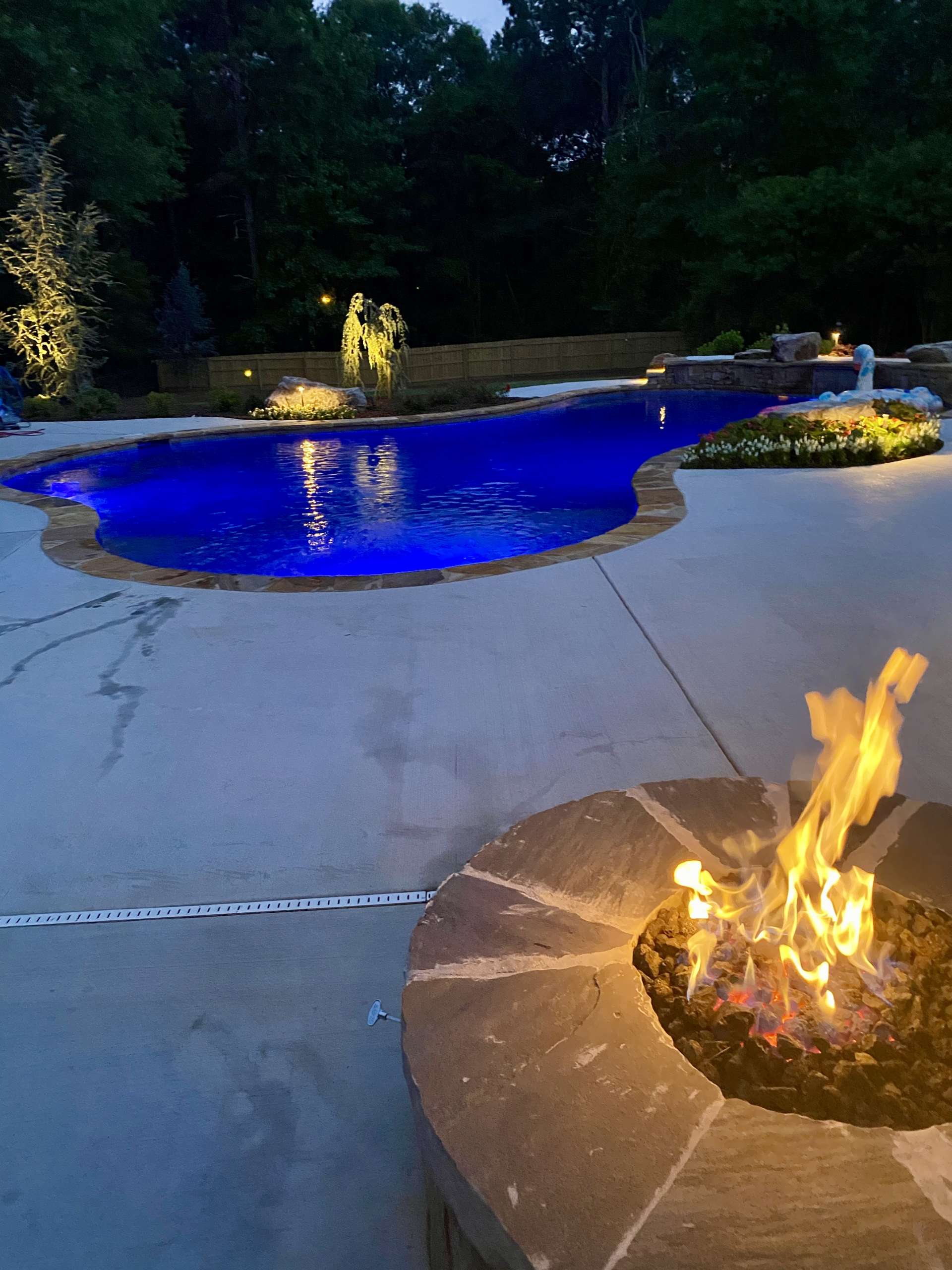 Firepit next to a pool lit by blue lights