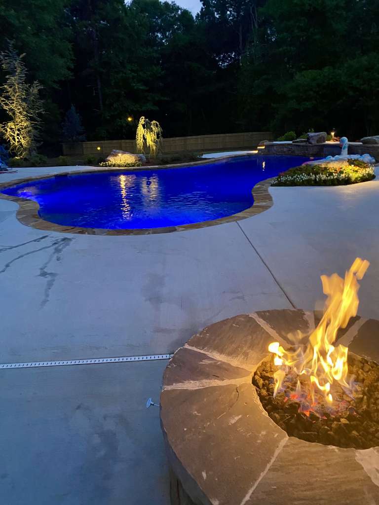 Firepit next to a pool lit by blue lights